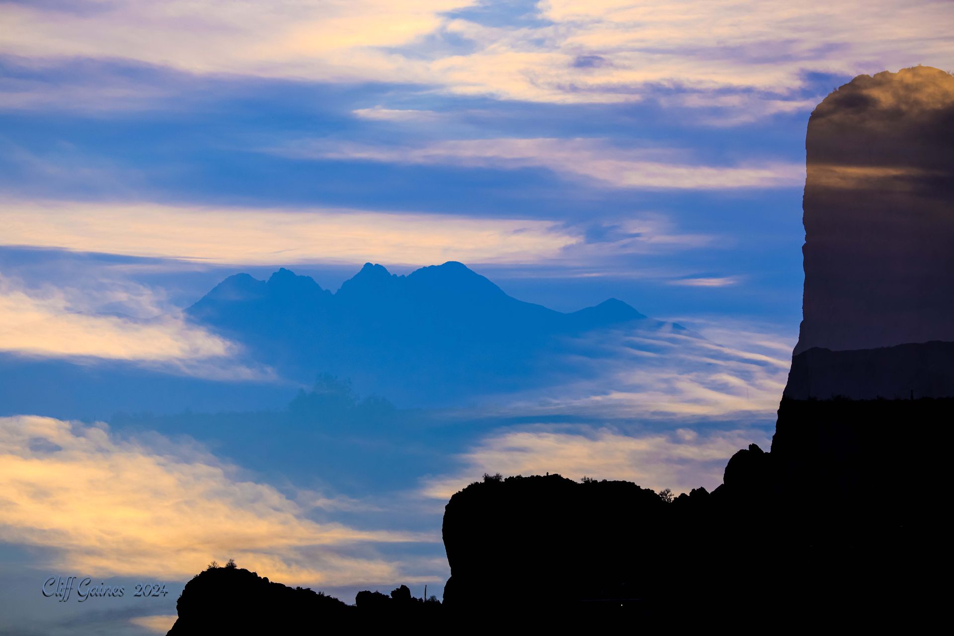 A mountain silhouetted against a cloudy sky at sunset