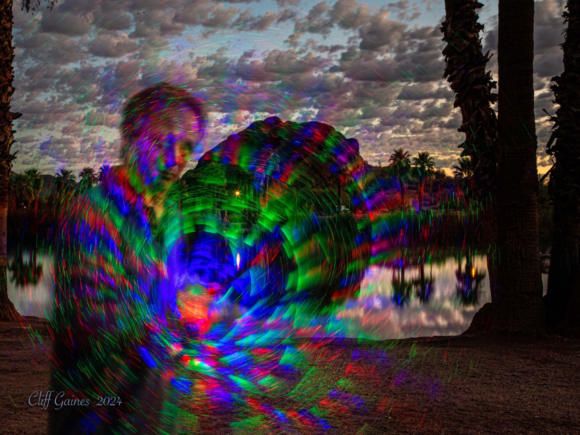 A man is standing in front of a lake with a colorful background.