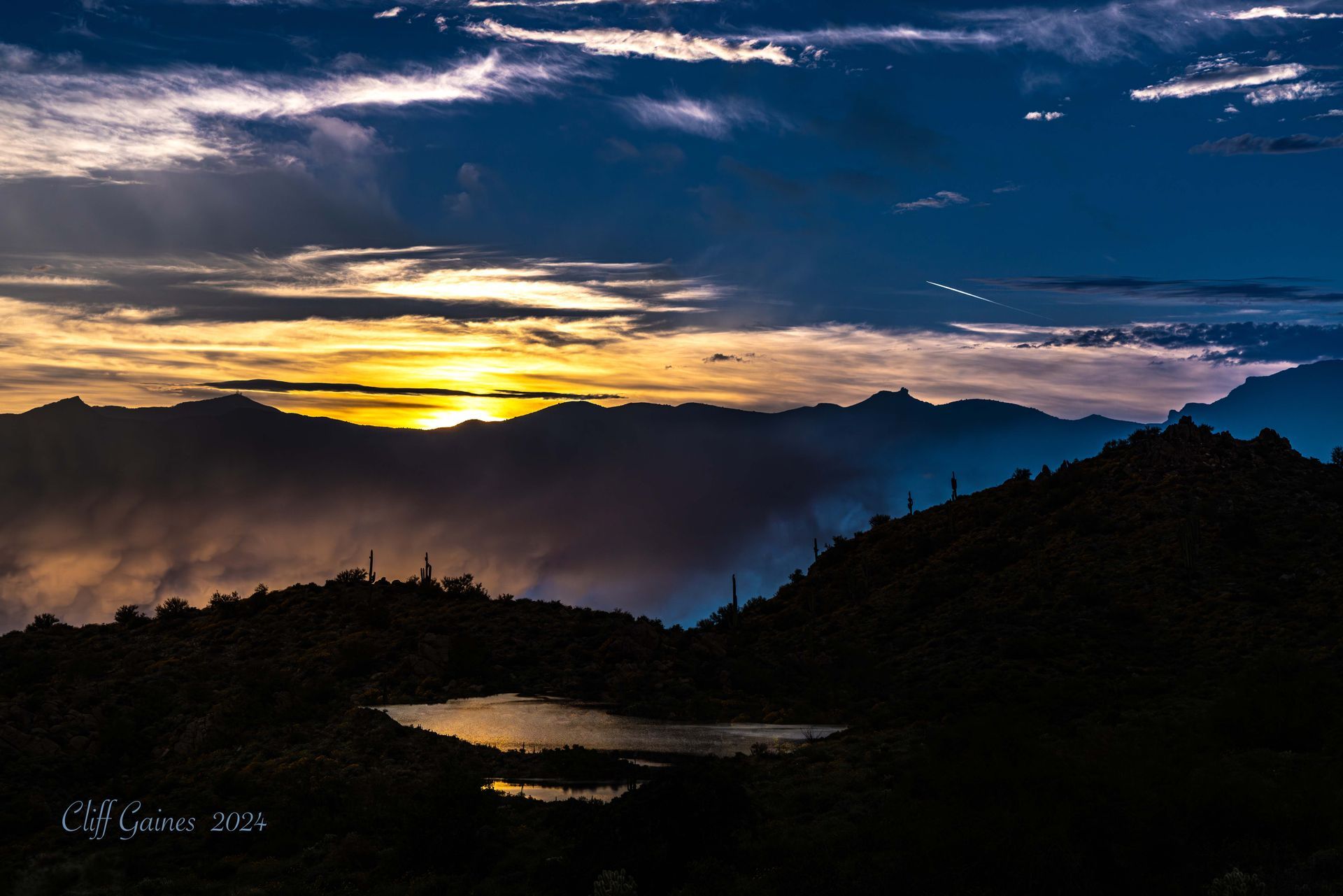 A sunset over a lake with mountains in the background