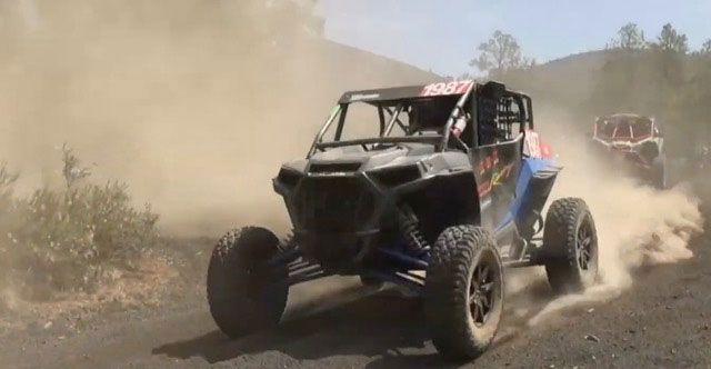 A couple of atvs are driving down a dirt road.
