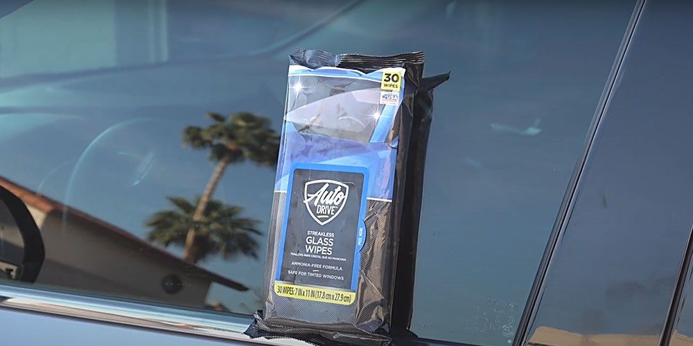 A bag of wipes is sitting on the windshield of a car.