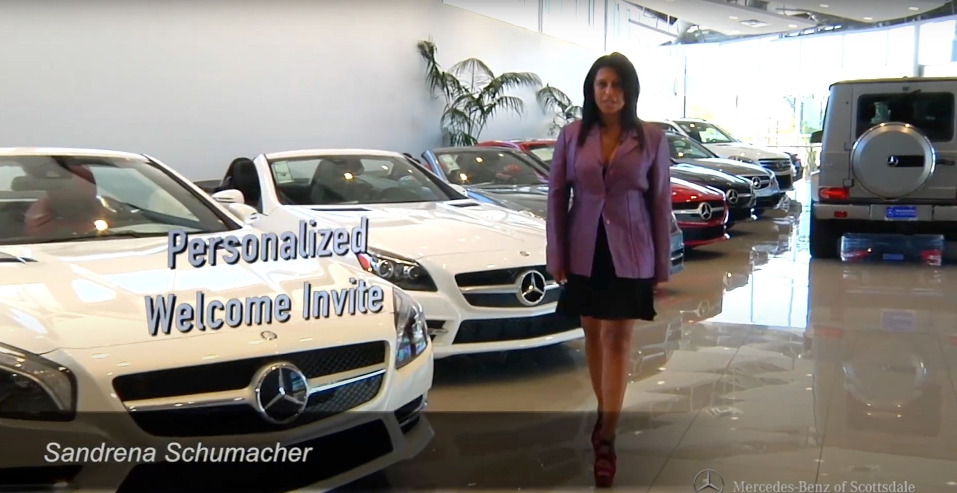 A woman in a purple jacket is standing in front of a mercedes showroom