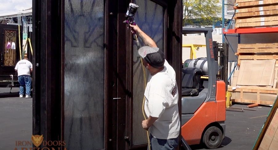 A man is working on a door with a forklift in the background.