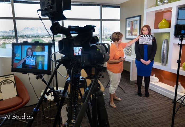 A woman is holding a clapper board in front of a camera