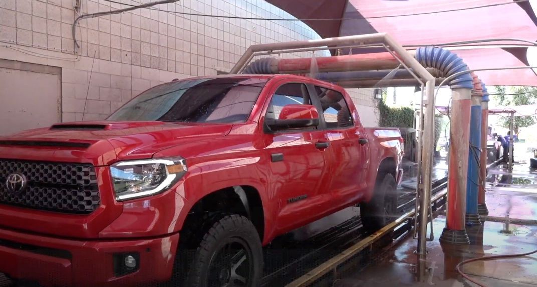 A red truck is being washed in a car wash.