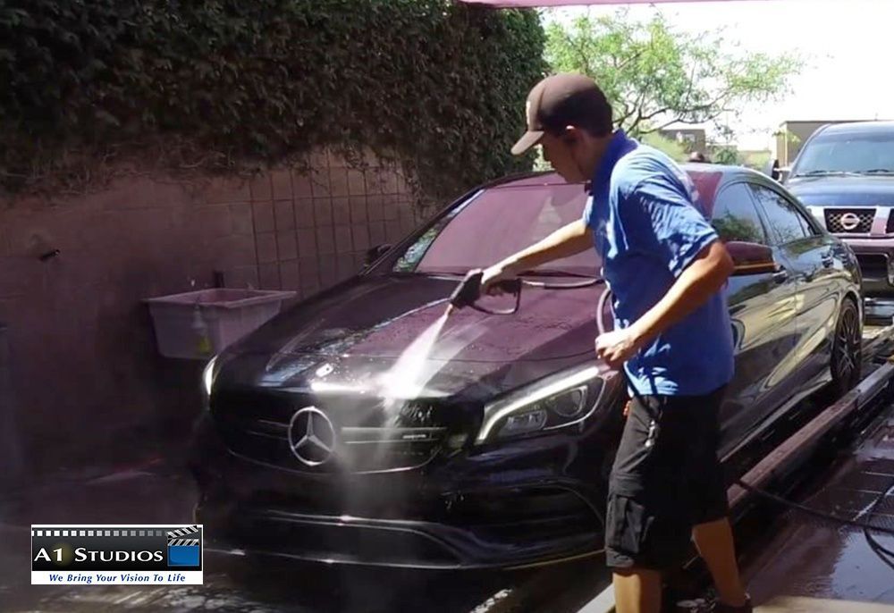 A man is washing a mercedes with a high pressure washer