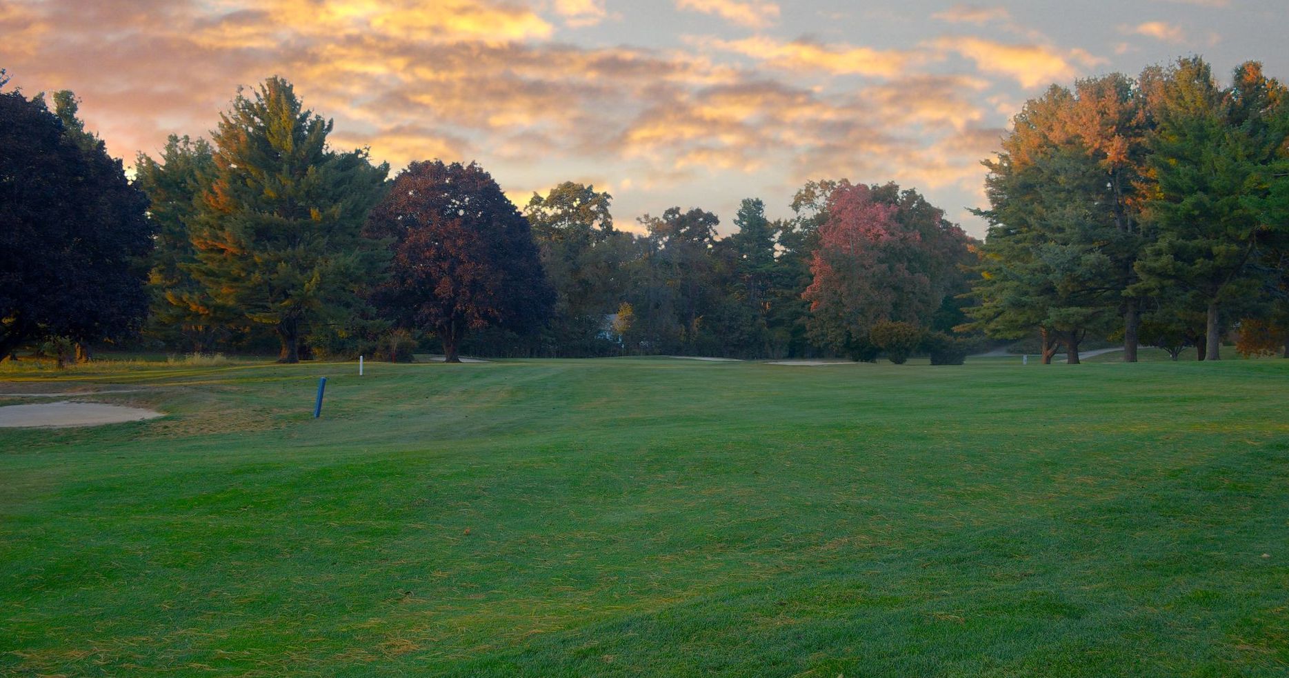 A golf course with a lake in the middle of it surrounded by trees.
