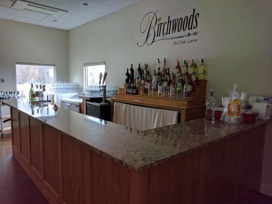 A bar with bottles of liquor and a sign that says birchwoods