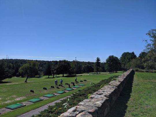 A group of people are practicing golf at a golf course