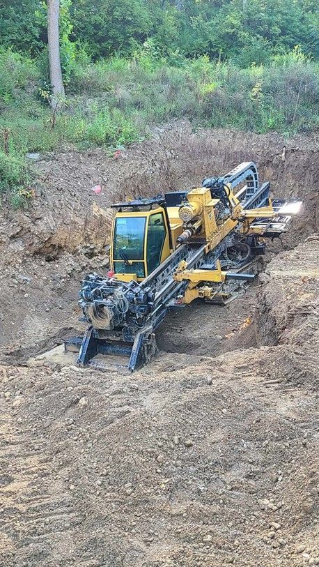 A pipe is being installed in a trench next to a sidewalk.