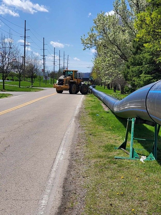 A group of construction workers are working on a pipe in the dirt.