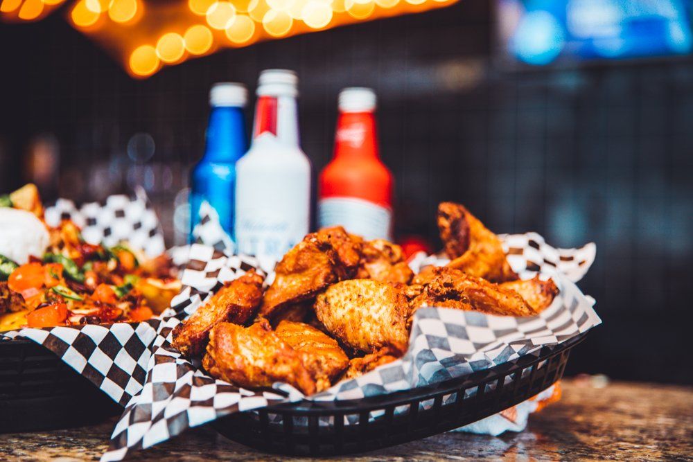 A basket of chicken wings is sitting on a table next to bottles of beer.