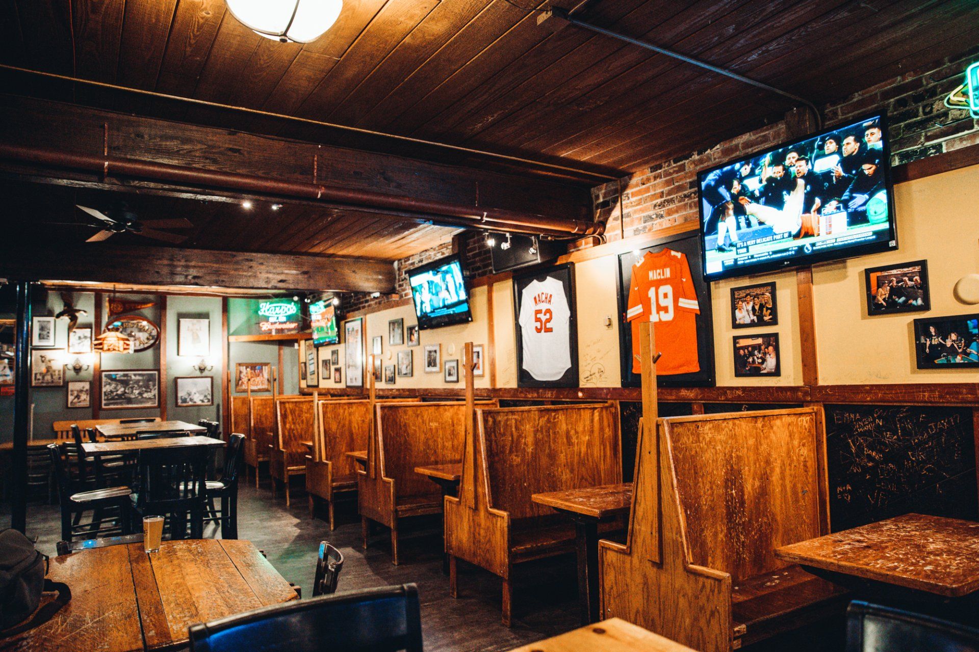A restaurant with tables , booths , and televisions on the walls.
