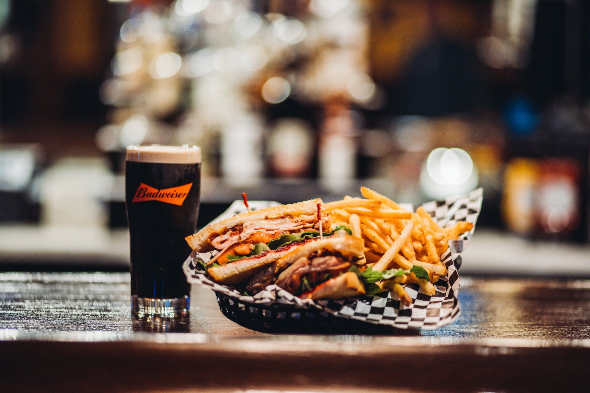 A basket of french fries and a glass of beer on a bar.