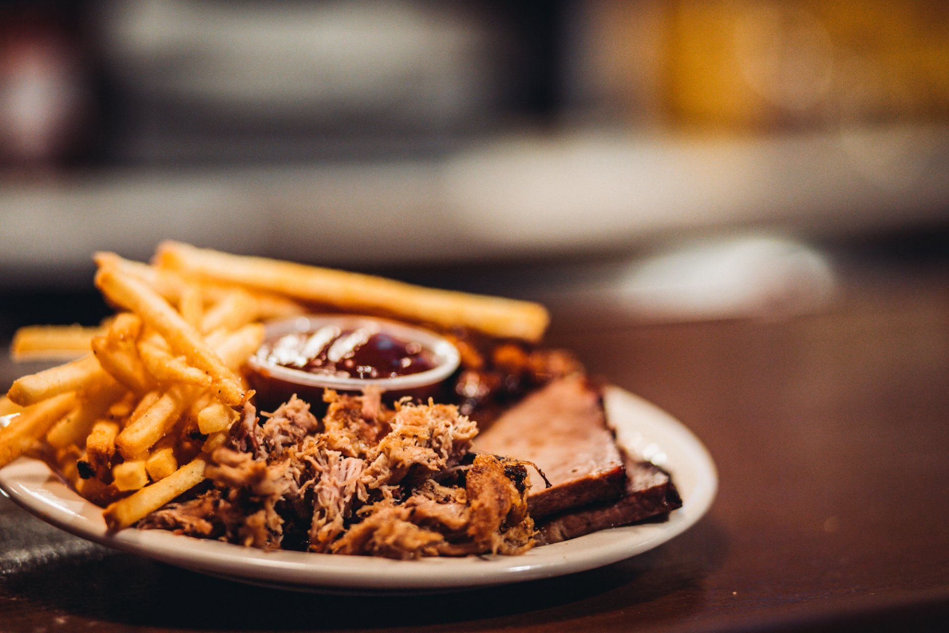 A white plate topped with meat and french fries on a wooden table.