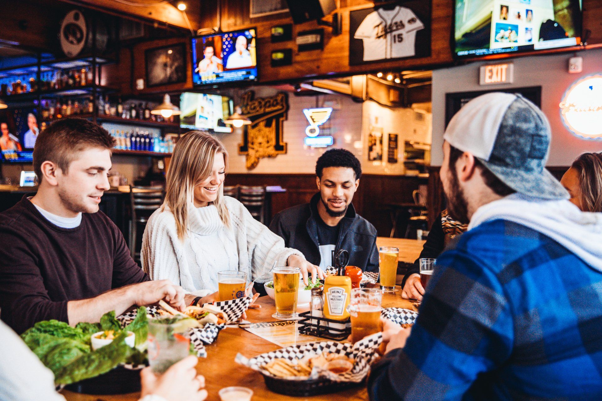 A group of people are sitting at a table in a restaurant eating food and drinking beer.