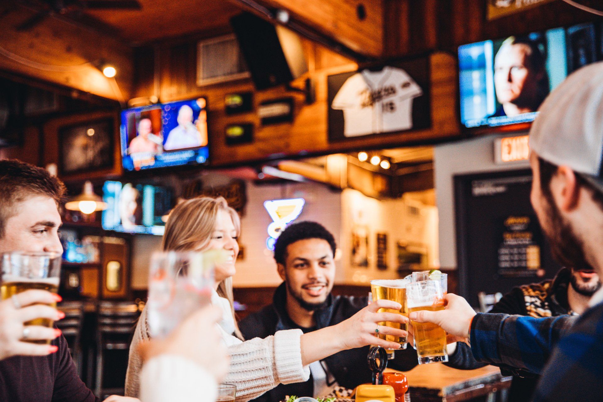 A group of people are toasting with beer in a bar.