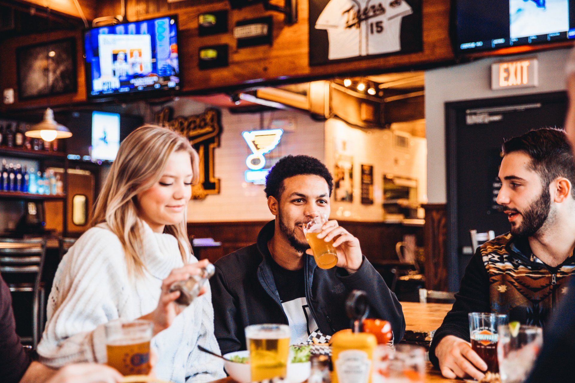 A group of people are sitting at a table in a restaurant drinking beer.