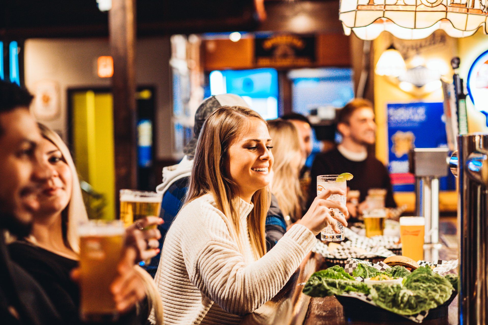 A group of people are sitting at a bar drinking beer.