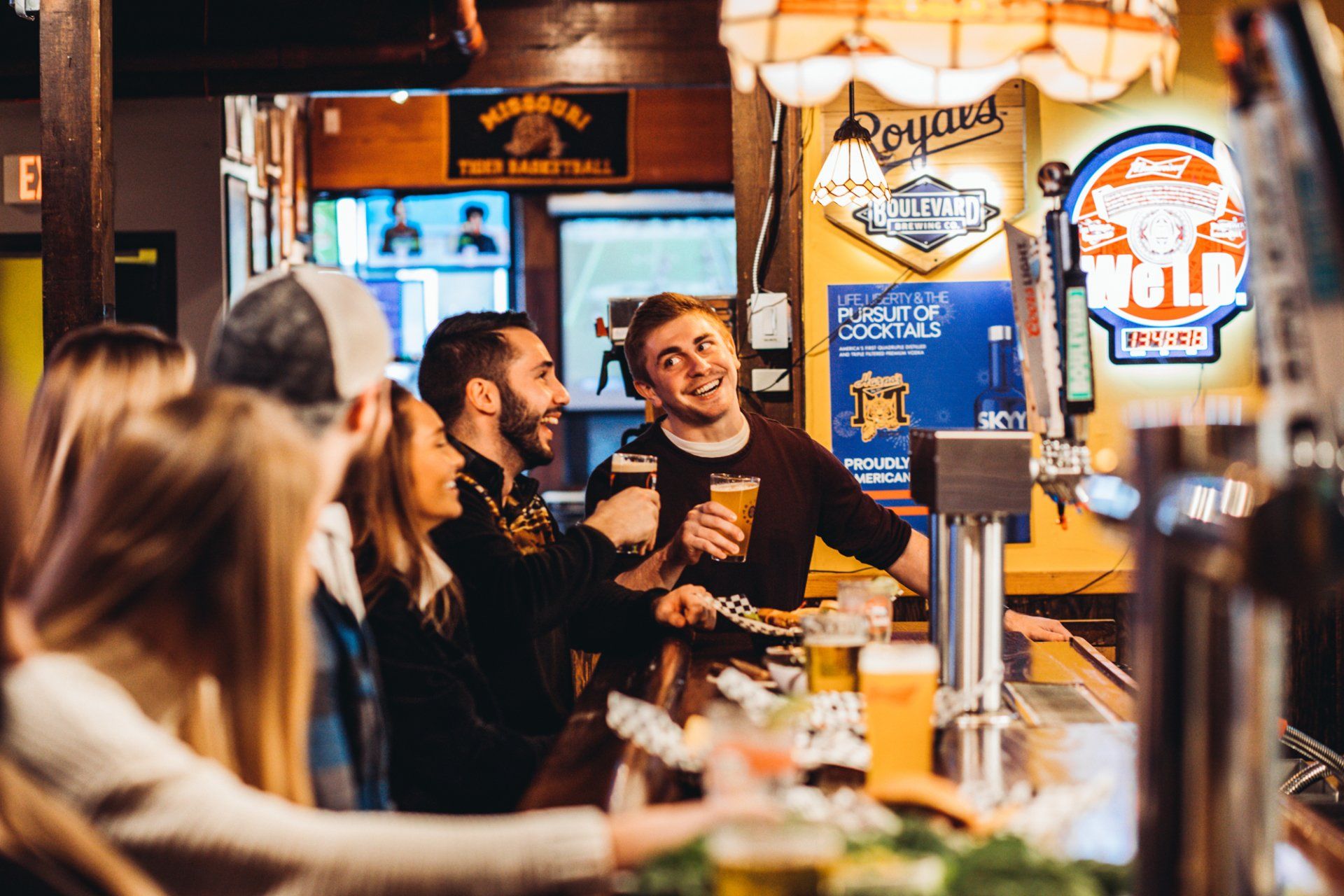 A group of people are sitting at a bar drinking beer.