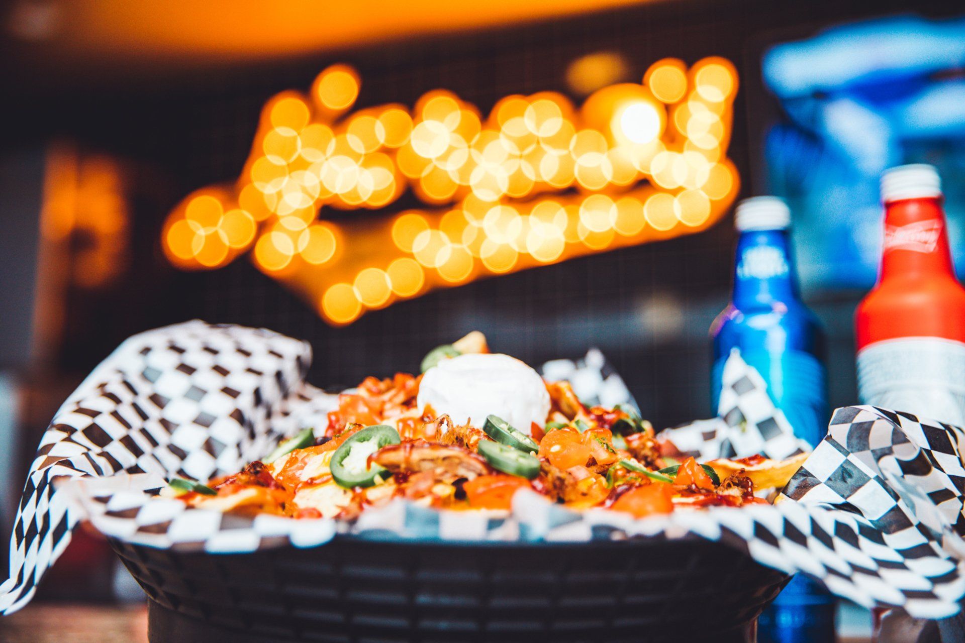 A basket of nachos is sitting on a table next to a bottle of beer.