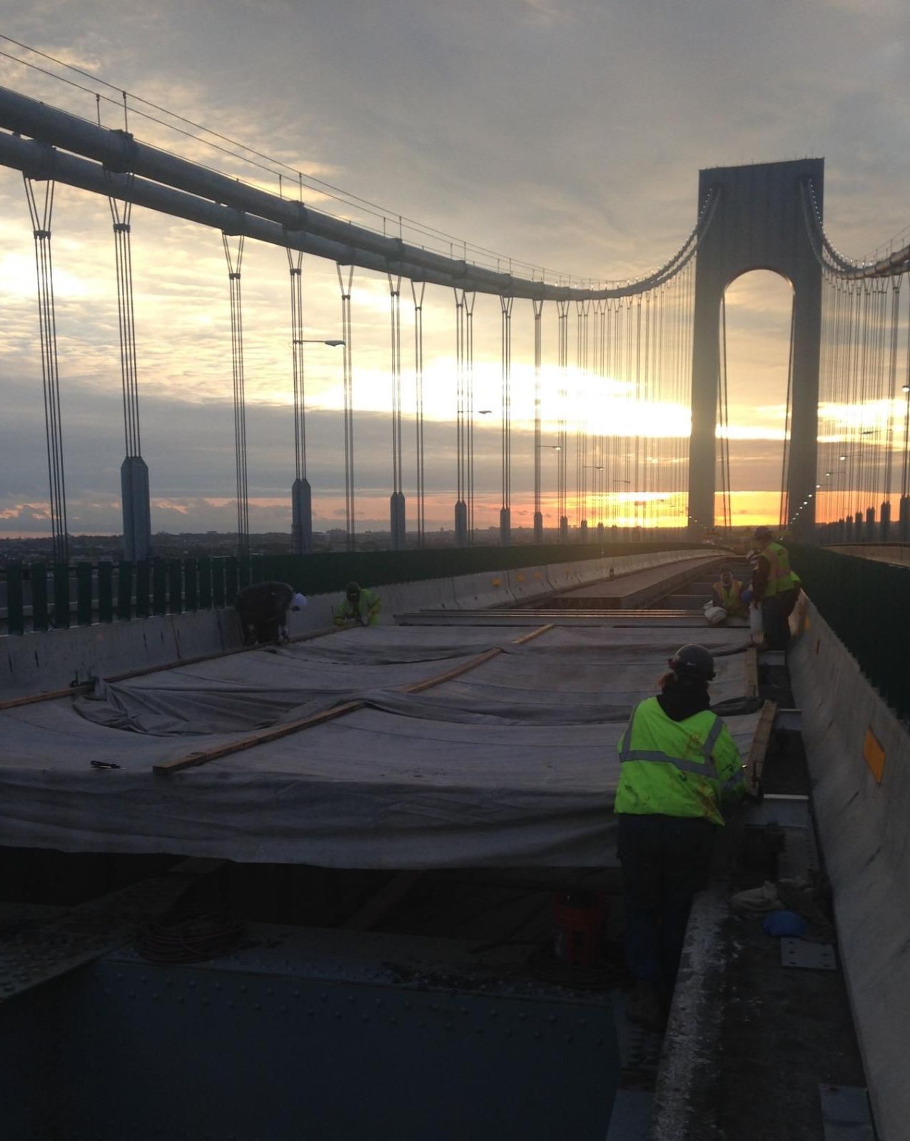 Construction workers are working on a bridge at sunset