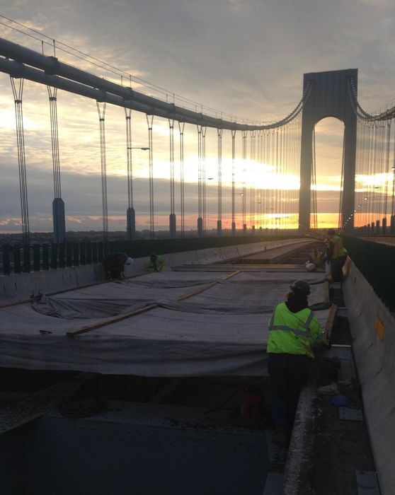 Construction workers are working on a bridge at sunset