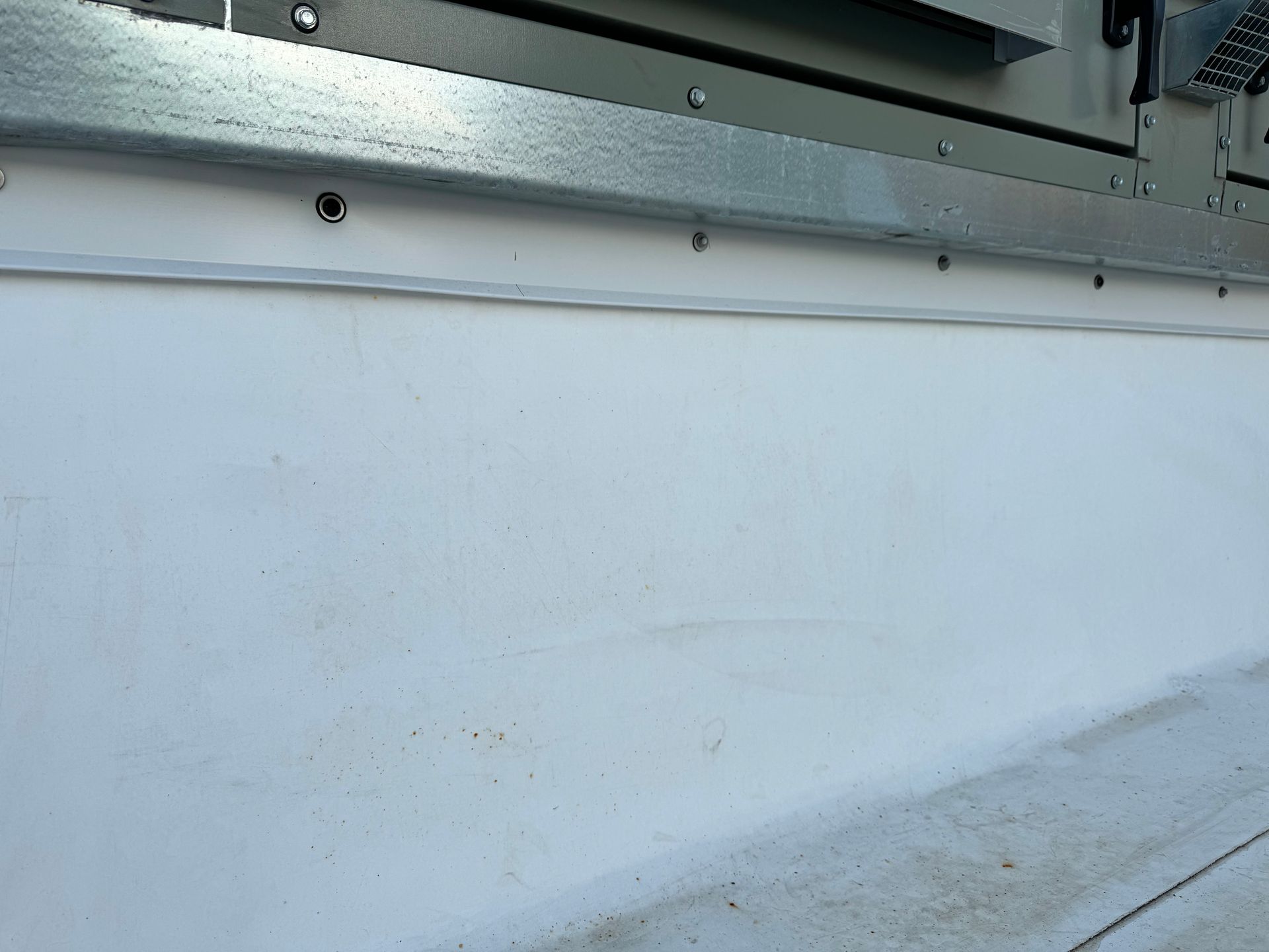 A white wall with a metal trim and screws on it