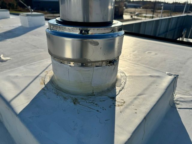 A metal pipe is sitting on top of a white roof.