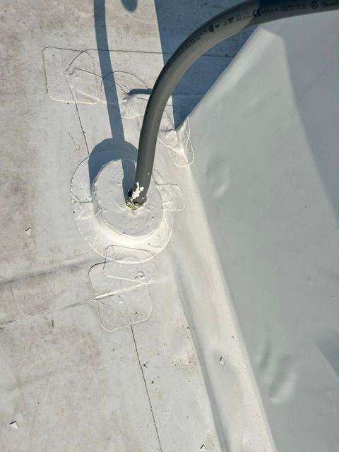 A black hose is connected to a hole in a white roof.