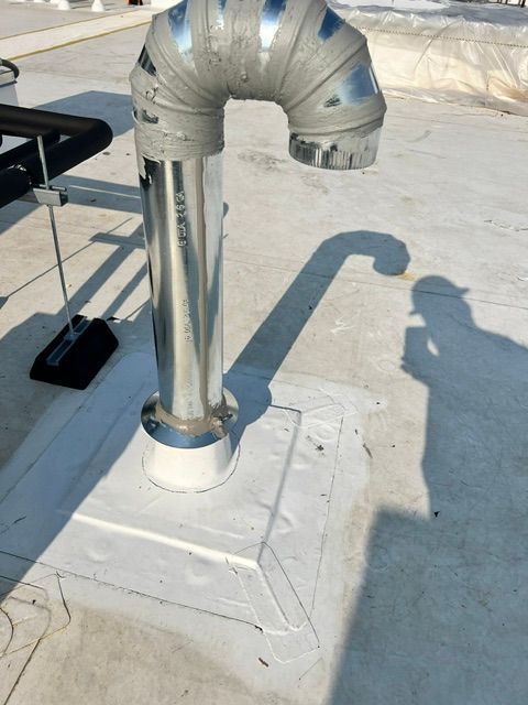 A stainless steel pipe is sitting on top of a white base