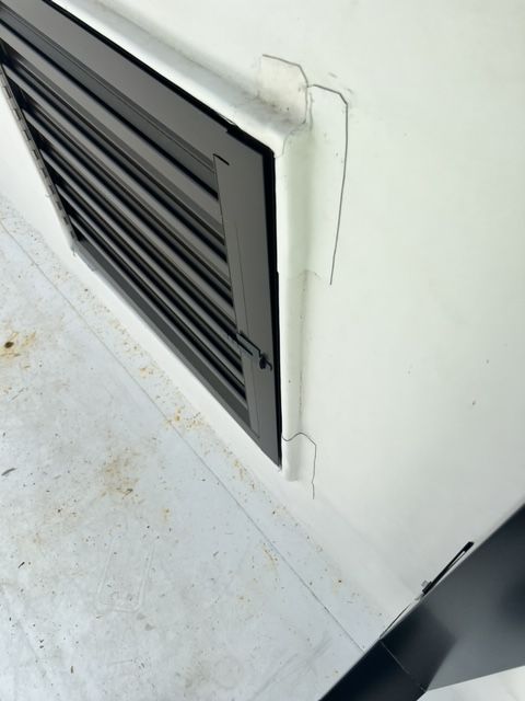 A white wall with a black shutter on it