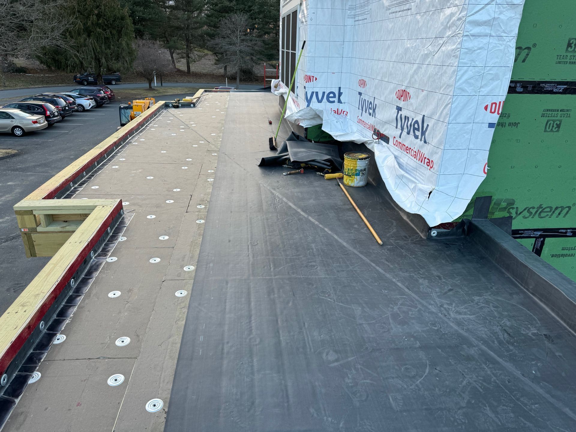 A roof is being installed on a building in a parking lot.