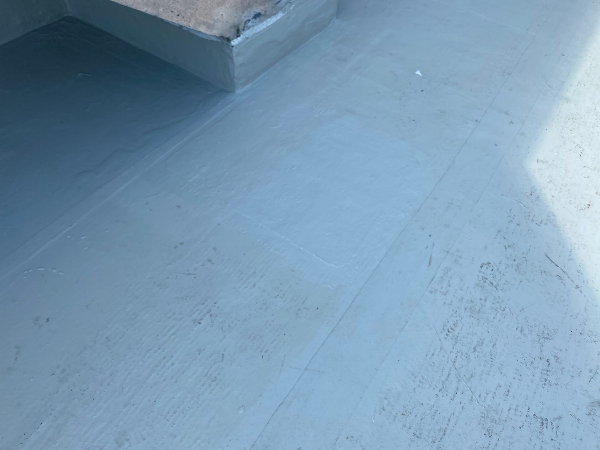 A close up of a blue concrete floor with a staircase in the background.