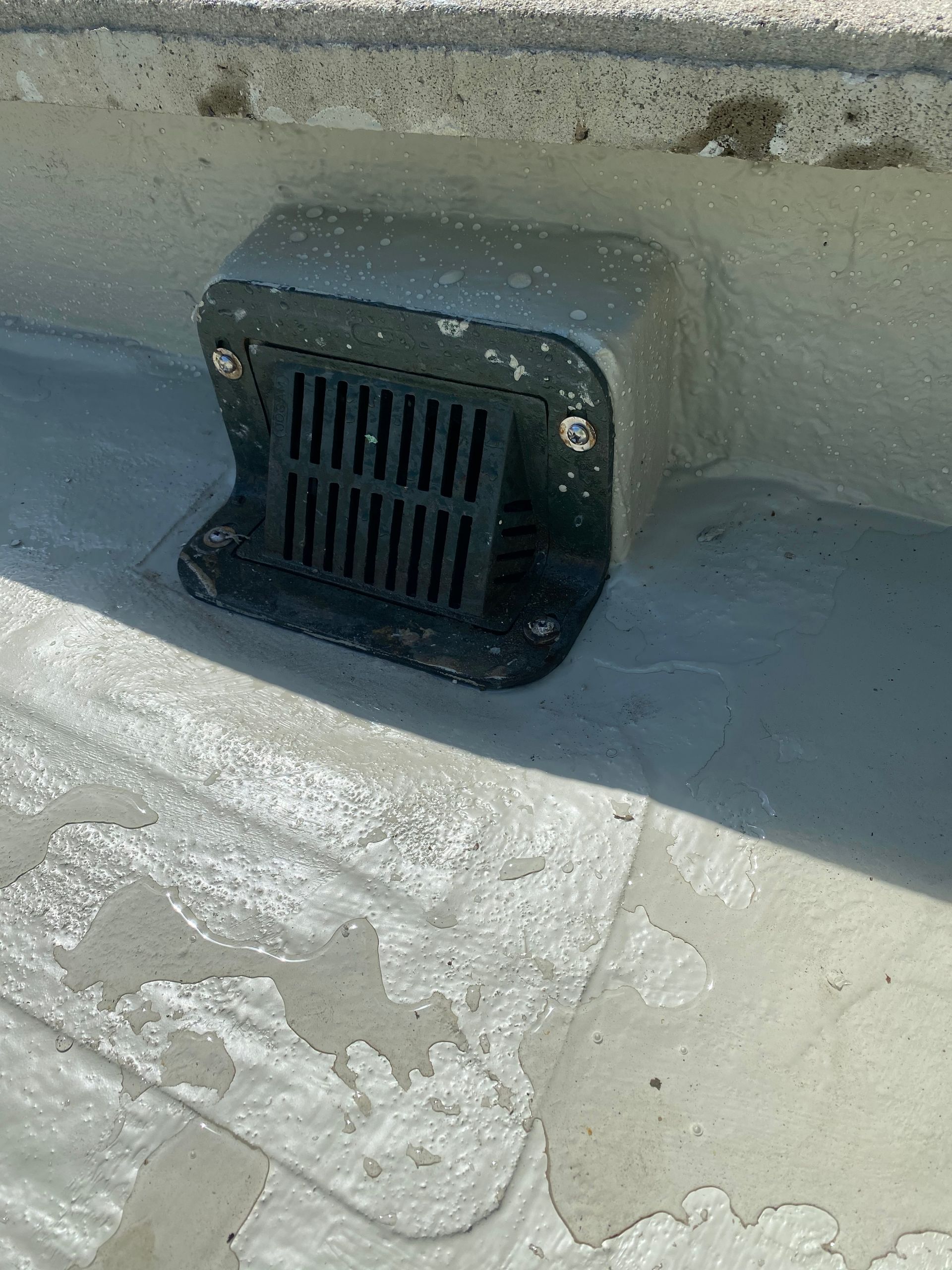 A close up of a drain on the side of a building.