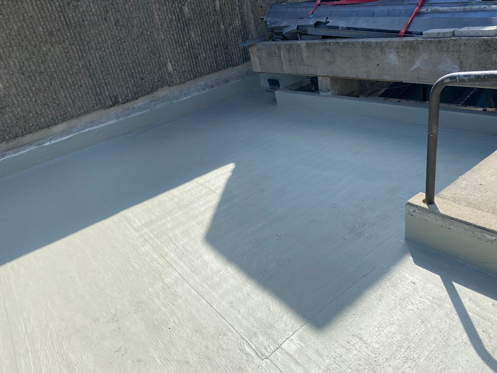 A concrete floor with a railing and a shadow on it.