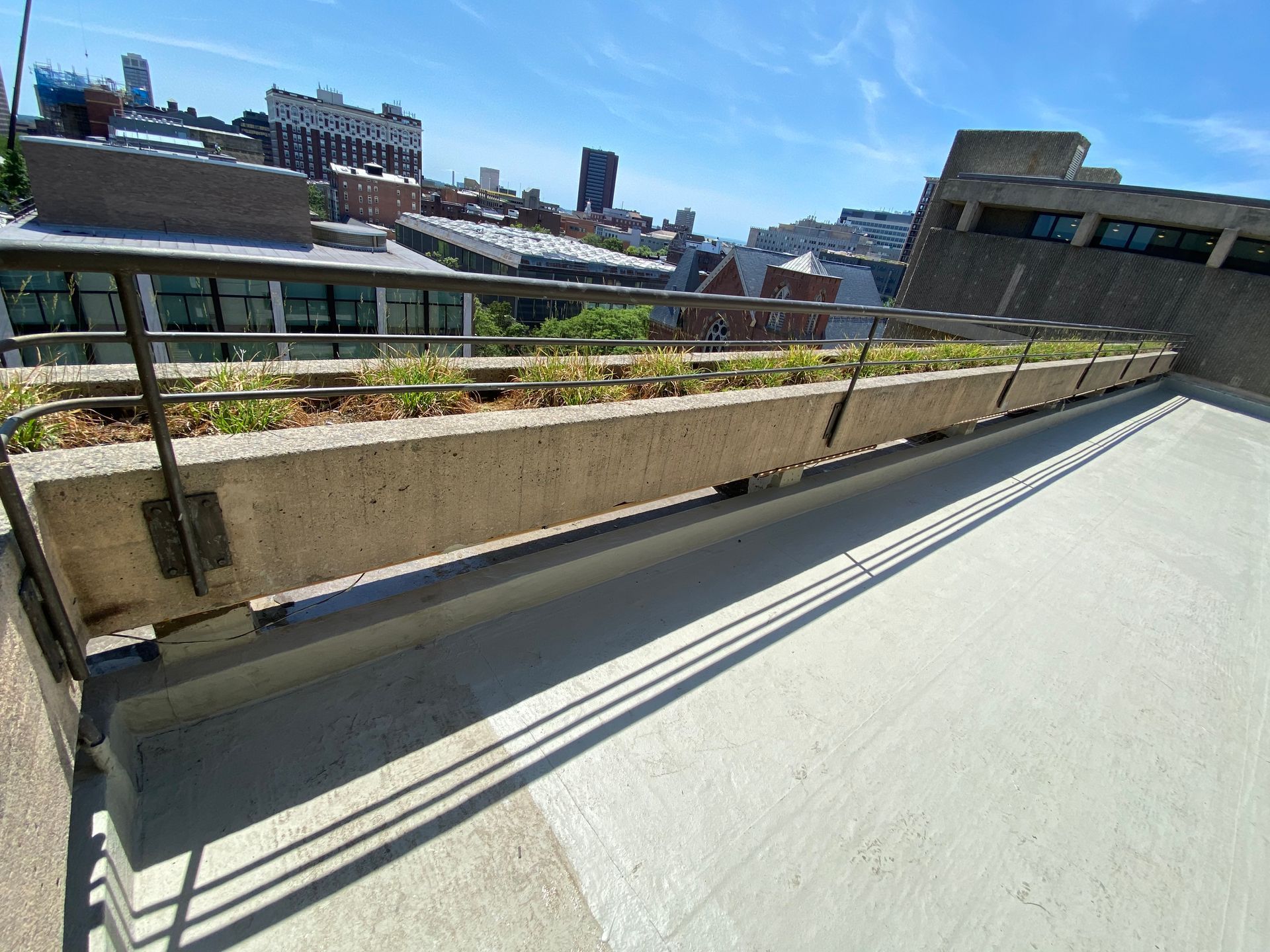 A concrete planter on the side of a building with a city in the background.