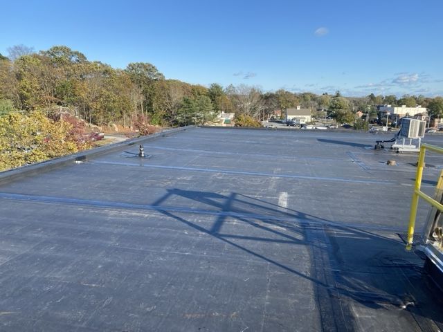 A black roof with a yellow railing and a blue sky in the background.