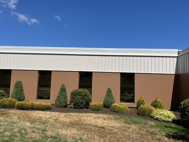 A large building with a lot of windows and bushes in front of it.
