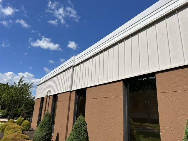 A brown building with a white roof and a blue sky in the background.