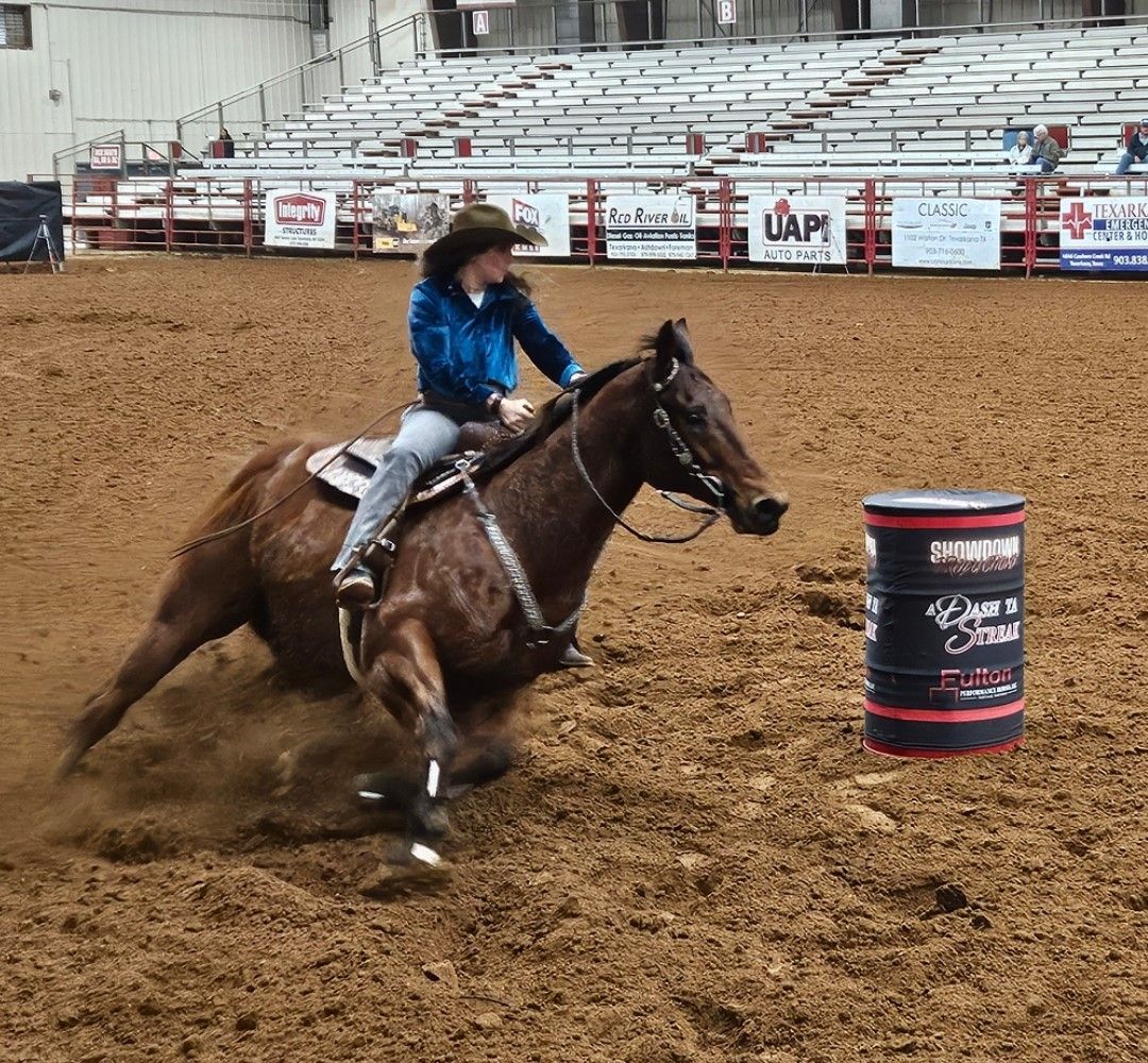 A woman is riding a horse in a rodeo arena