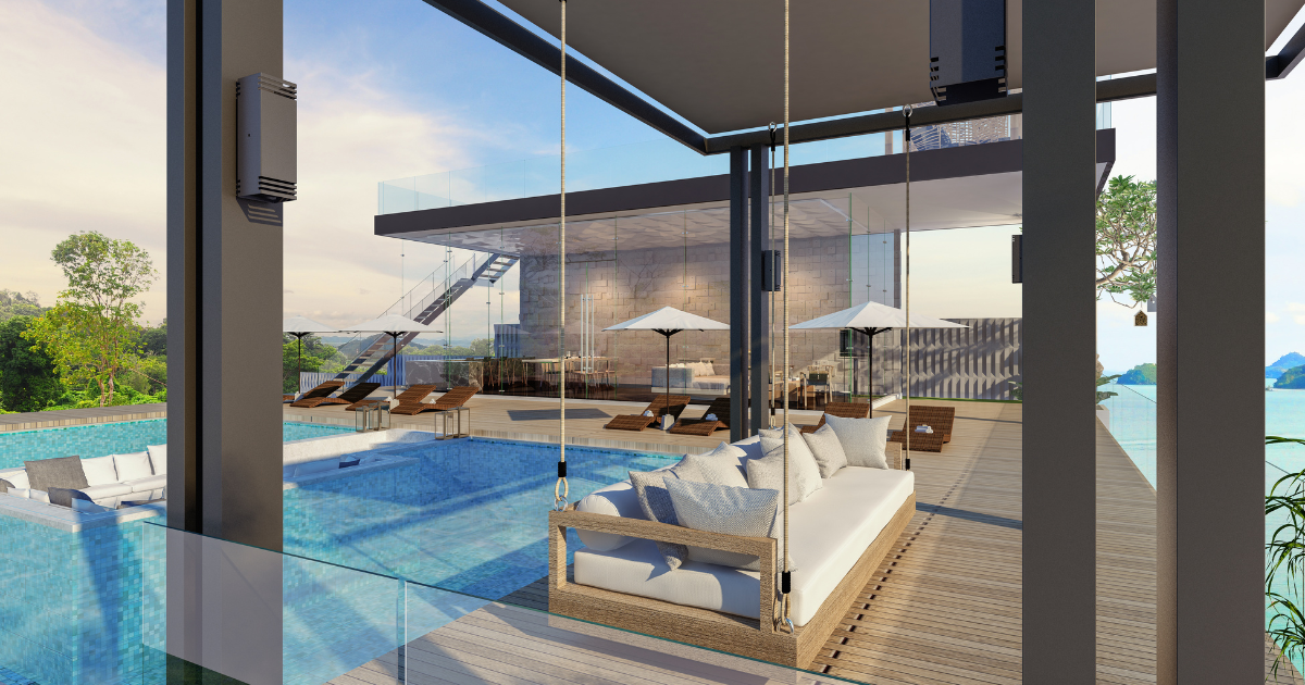 Poolside view with swing, glass walls, and modern building overlooking the ocean.