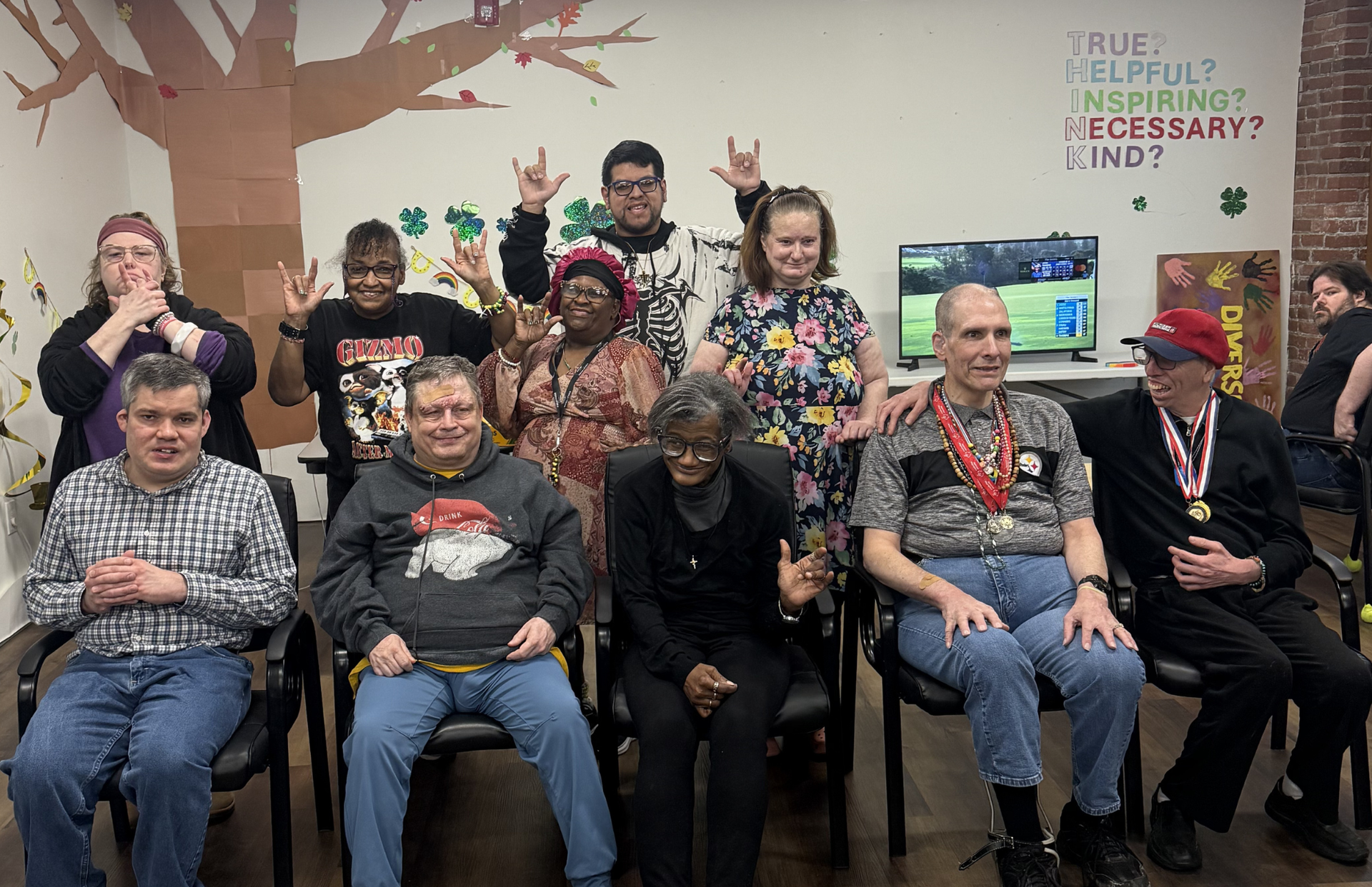 Group of people in purple shirts cheer with gold pom-poms at an indoor event.