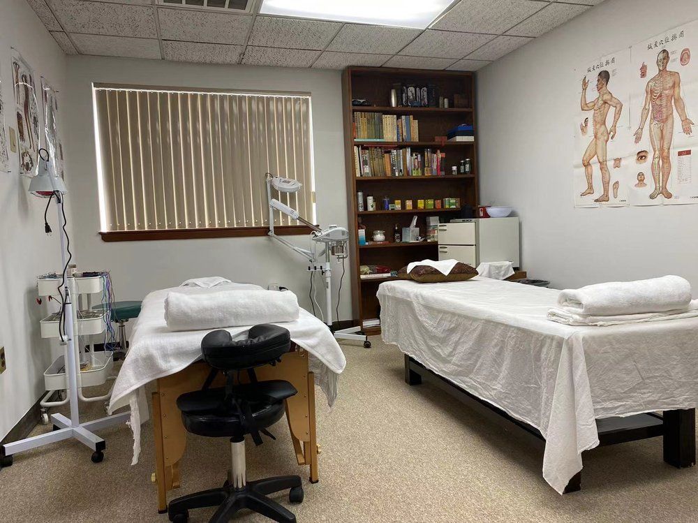 Two massage tables in a therapy room with medical equipment and anatomical charts.