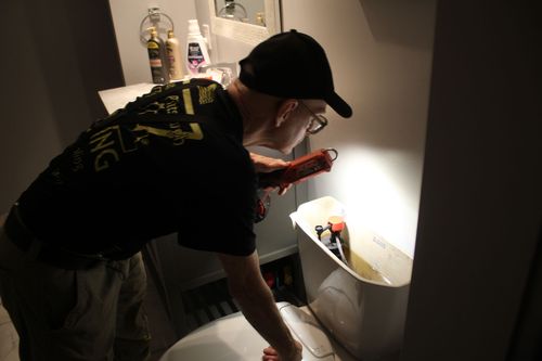 A toilet with a wrench and pliers on top of it.