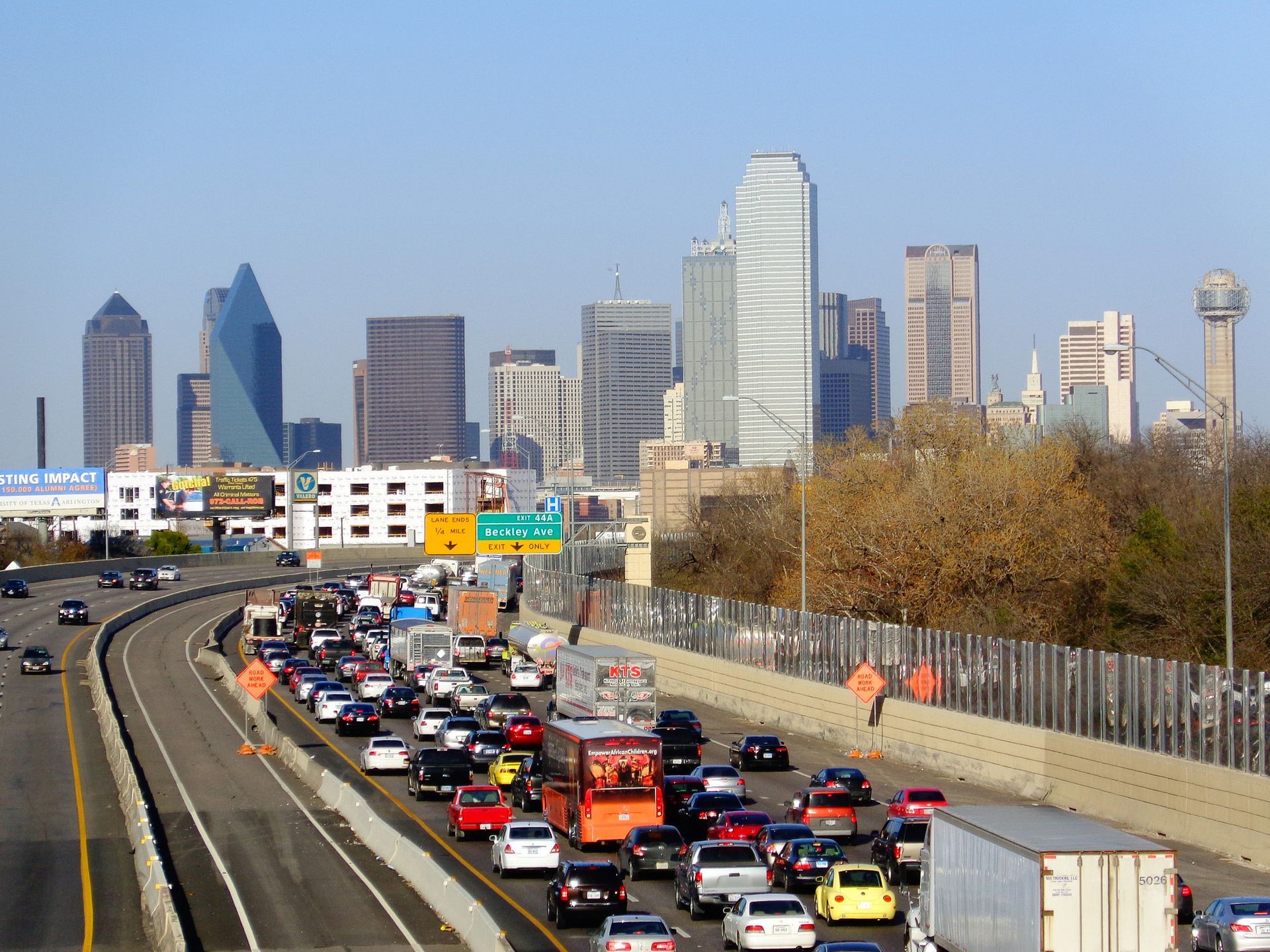 Dallas skyline over I-35 traffic at rush hour, dense cars and trucks on the highway, illustrating DFW driving risk for our car-wreck 10-step checklist.