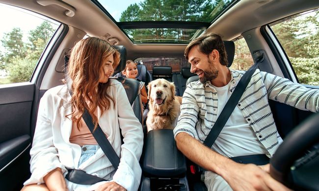 A family is sitting in the back seat of a car with a dog.