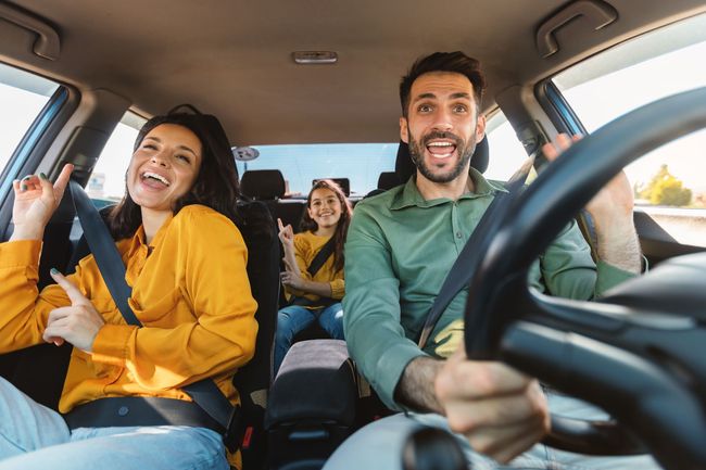 A family is sitting in the back seat of a car.