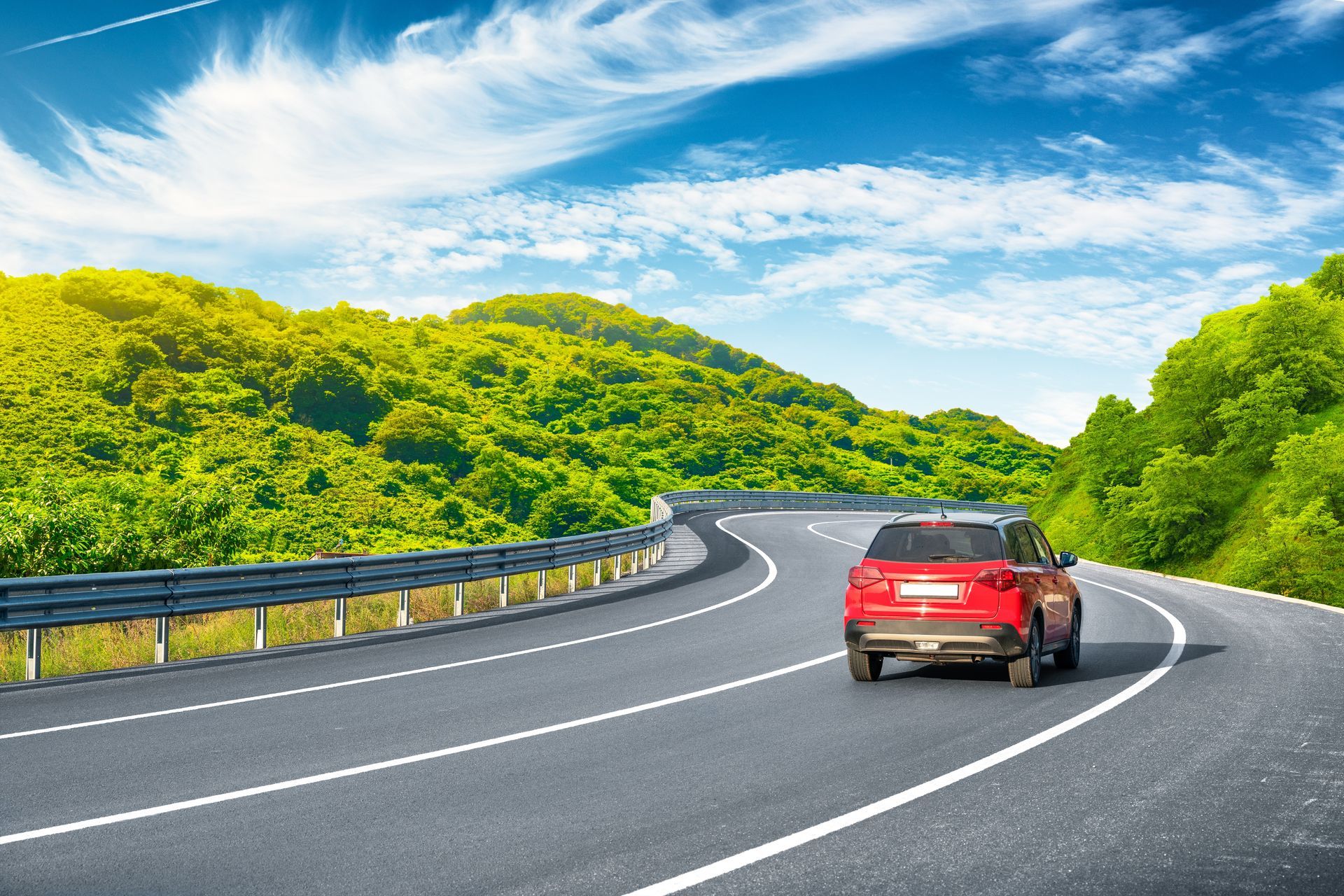 A red car is driving down a curvy road.