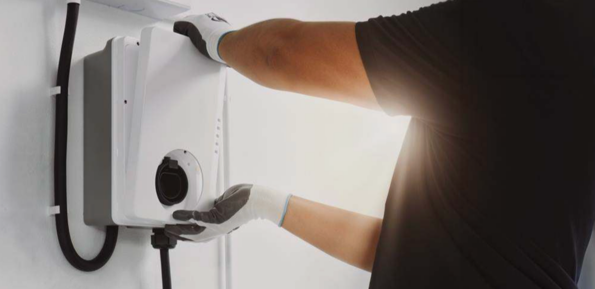 Electrician installing a wall-mounted EV home charging unit.
